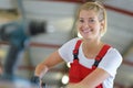 Female apprentice using drill in factory