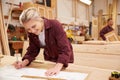 Female Apprentice Working With Plans In Carpentry Workshop