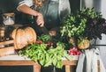 Female in apron cutting various vegetable ingredients on counter