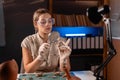 Female archaeologist with magnifying glass working late at night in office