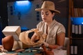 Female archaeologist working late night in office prepares a parcel with an antique vase found at excavation site Royalty Free Stock Photo