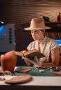 Female archeologist work late night in office research ancient civilization cultural artifact, reading book about Royalty Free Stock Photo