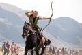 Female archer shooting an arrow on horseback.