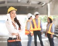 Female architect or engineer holding blue print paper, standing in front of her team smiling and looking at camera Royalty Free Stock Photo