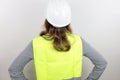 Female architect wearing reflecting jacket and hardhat standing backwards with hands on hips looking up. Royalty Free Stock Photo