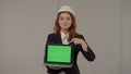 A female architect is holding a laptop screen facing forward and pointing at its green screen. Portrait of a business Royalty Free Stock Photo