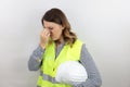 Female architect holding safety helmet under arm, tired rubbing nose and eyes feeling fatigue and headache. Royalty Free Stock Photo