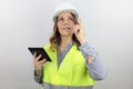 Female Architect holding tablet, pointing up finger thinking about question with happy face standing and smiling. Royalty Free Stock Photo