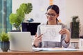 Female Architect In Office Sitting At Desk Showing Plans For New Building On Video Call Royalty Free Stock Photo