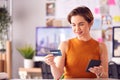 Female Architect In Office Working At Desk Making Online Purchase Using Credit Card On Mobile Phone Royalty Free Stock Photo