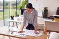 Female Architect Standing Working In Office Studying Plans For New Building Royalty Free Stock Photo