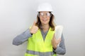 Female architect  wearing hardhat smiling happy and thumbs up, standing with smile on face holding building plans. Royalty Free Stock Photo