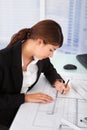 Female Architect Working On Blueprint At Desk Royalty Free Stock Photo