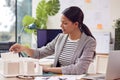 Female Architect Working In Office Sitting At Desk Studying Model Of New Building Royalty Free Stock Photo