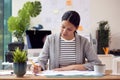 Female Architect Working In Office Sitting At Desk Studying Plans For New Building Royalty Free Stock Photo