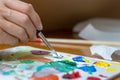 Female artist hand mixing colors with a paintbrush on a color palette