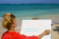 A female artist painting on the beach