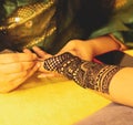 A female artist performing mehandi or henna design on female hand