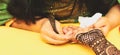 A female artist performing mehandi or henna design on female hand