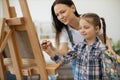 Female artist teaching girl funny shapes by guiding her hand