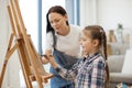 Female artist teaching girl funny shapes by guiding her hand