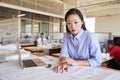 Female Asian architect studying planes in open plan office Royalty Free Stock Photo