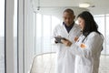 Female Asian doctor talking with African American doctor with tablet