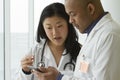 Female Asian doctor talking with African American doctor with tablet Royalty Free Stock Photo