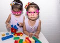 Female asian identical twins sitting on chair with white background. Wearing purple dress and accessories. Standing and playing on