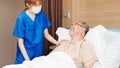 Female Asian nurse wear mask care and check on senior male smile patient in private room in hospital bed. Medical healthcare Royalty Free Stock Photo