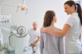 Female assistant talking to girl patient in front of dentist at clinic