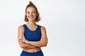 Female athelte in sportswear cross arms on chest. Athletic sportswoman in confident pose smiling at camera, white