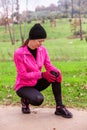 Female athlete hurting from a knee injury on a cold winter day on the training track of an urban park.