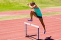 Female athlete jumping above the hurdle