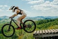 female athlete mountainbiker jump drop downhill in flight