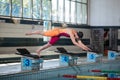 Female athlete preparing for a dive start and jumping into the pool Royalty Free Stock Photo