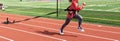 Female athlete pulling sled with weight down a red track