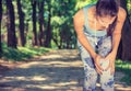 Female athlete runner touching knee in pain, fitness woman running in park.