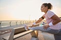 Female athlete, sportswoman in pink t-shirt stretching legs before morning jog. Sportswoman working out outdoor, standing on a Royalty Free Stock Photo