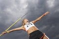 Female athlete throwing javelin against cloudy sky low angle view Royalty Free Stock Photo