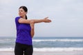 Female athlete warming up and stretching the upper body before running at the beach Royalty Free Stock Photo