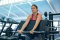 Female athletic exercising with barbell on preacher bench in fitness center