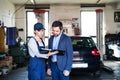 Female auto mechanic talking with customer, explaining repair, problem. Scheduling date of annual maintenance. Beautiful Royalty Free Stock Photo