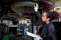 Female auto mechanic work in garage, car service technician woman check and repair customerÃ¢â¬â¢s car at automobile service center, Royalty Free Stock Photo