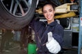 Female auto mechanic work in garage, car service technician woman give thumb up, repair customer car at automobile service center Royalty Free Stock Photo