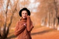 Female autumn portrait. a lonely beautiful blonde girl in a brown warm sweater and black hat stands alone and looks into the Royalty Free Stock Photo