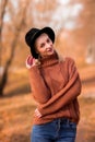 Female autumn portrait. vertical photo. beautiful blonde girl in a brown warm sweater and black hat smiles. the park Royalty Free Stock Photo