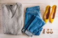Female autumn and winter clothes flat lay on wooden background. Gray sweater, jeans and yellow shoes Royalty Free Stock Photo