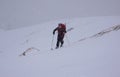 A female backcountry skier hiking up on a high alpine mountain in the Austrian Alps in winter in bad weather