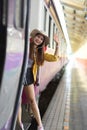 Female backpacker stepping down of the train and smiling to celebrate her journey